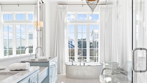 Un baño moderno con bañera independiente, ventanas amplias y cabina de ducha con mampara de vidrio.