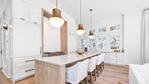 Una cocina moderna con armarios blancos, una isla de madera e iluminación colgante.