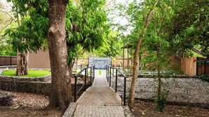 A paved pathway leading to a building with a stone wall and a wooden fence.