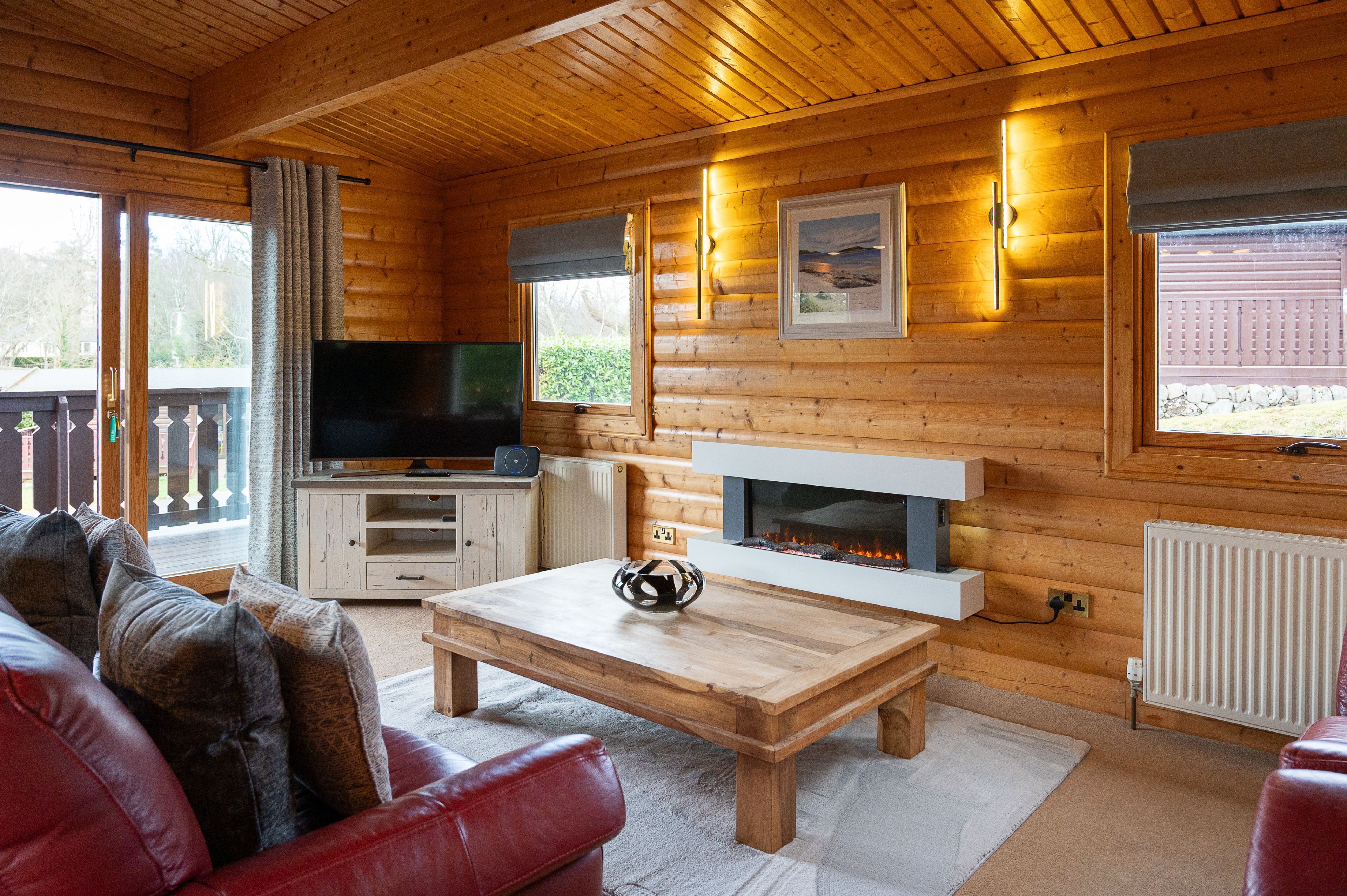 A cozy cabin interior with a wooden interior, a fireplace, a television, and a comfortable seating area.