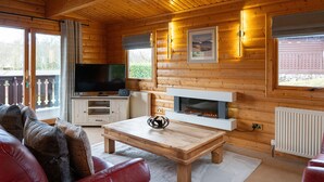 A cozy cabin interior with a wooden interior, a fireplace, a television, and a comfortable seating area.