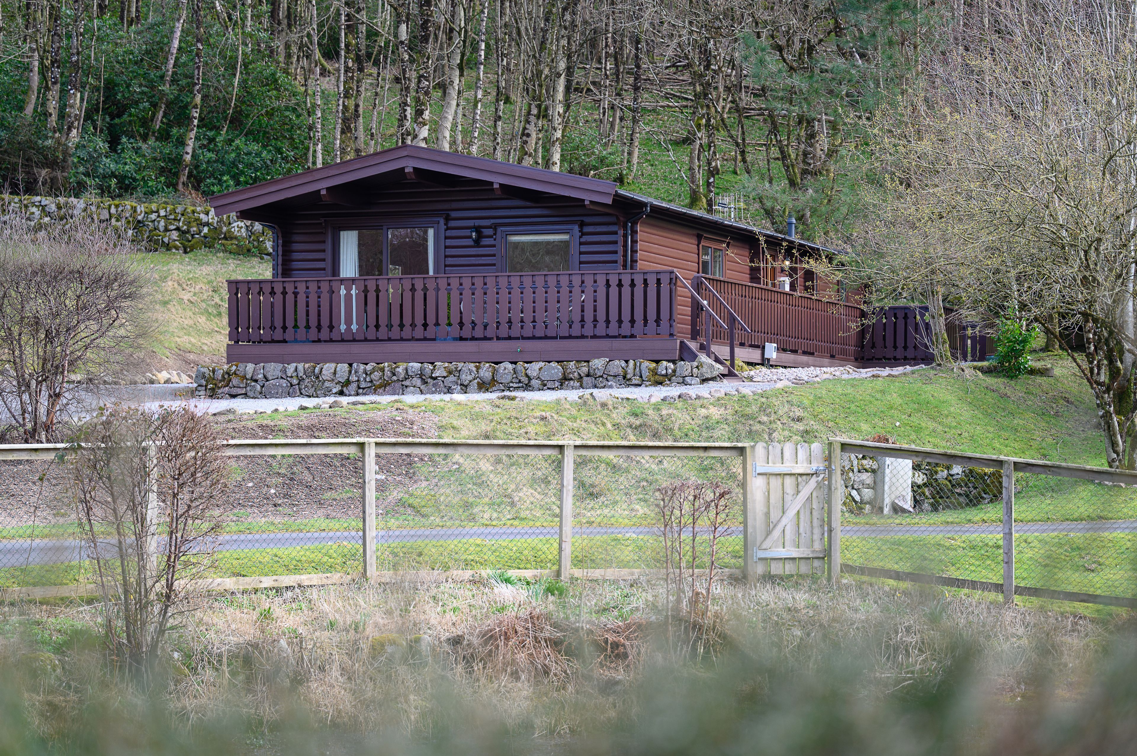 Une cabane avec une façade en bois, un balcon et des fondations en pierre.