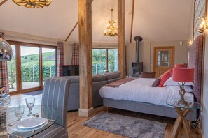 A cozy bedroom with a bed, a sofa, a dining table with glasses, and a fireplace. - Silver Birch Treehouse -  a treehouse that sleeps 2 guests  in 0 bedrooms (Glenshee)