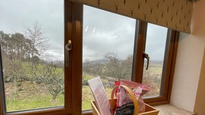 Ein Zimmer mit einem Fenster, das auf eine ländliche Landschaft blickt. Ein Holzkorb mit dem Schriftzug „Bitte nicht stören“ steht auf dem Fensterbrett.