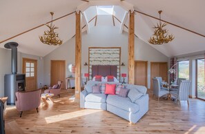 A spacious loft with a high ceiling, a fireplace, a large sofa, and a dining area.