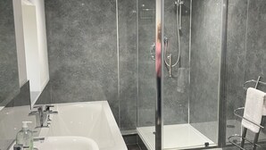 A modern bathroom with a large white sink, a glass-enclosed shower, and dark tiled walls. - Smiddy Cottage -  a cottage that sleeps 4 guests  in 2 bedrooms (Glenshee)