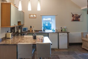 Een kleine keuken met een eethoek, een raam en een radiator.