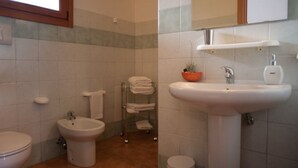 Ein Badezimmer mit Toilette, Bidet, Waschbecken und Handtuchhalter.