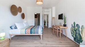 A modern bedroom with a bed, bedside table, and a desk with a chair. There are cacti on the wall and a television mounted on the wall. - 7Rooms - The Countryside (Lecce)
