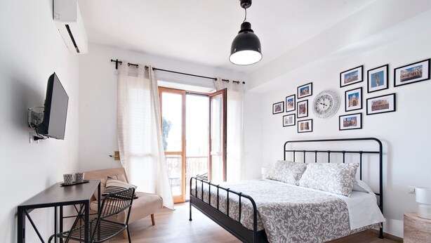 A bedroom with a bed, a desk, a chair, a hanging light, and a balcony with curtains. - 7Rooms - The City-Lecce Selection (Lecce)