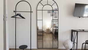 A room with a mirrored wardrobe, a small round table, a chair, a TV mounted on the wall, and a bed with a headboard. - 7Rooms - The City-Lecce Selection (Lecce)