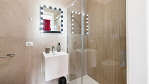 A modern bathroom with a glass shower enclosure, a vanity with a mirror and lights, and a toilet. - 7Rooms - The Party - Lecce Selection (Lecce)