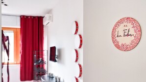 A room with a red curtain, a small table with cups, and a decorative circular sign on the wall. - 7Rooms - The Party - Lecce Selection (Lecce)