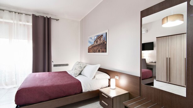 A modern hotel room with a bed, bedside table, and a large mirror. - Kalurya - Baroque - Lecce Selection (Lecce)