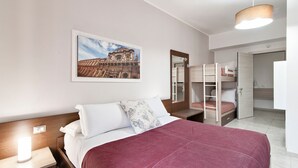 A hotel room with a bed, a bedside lamp, a bunk bed, a mirror, and a framed picture on the wall. - Kalurya - Baroque - Lecce Selection (Lecce)