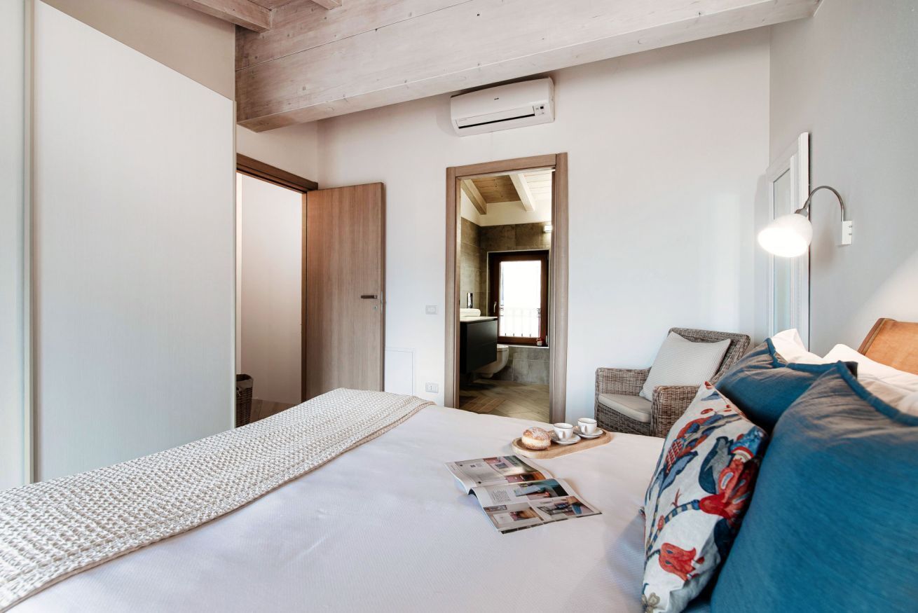 Hotellihuoneessa on sänky, luku- tai oleskelualue, sohva sekä pieni pöytä, jonka päällä on lehti ja leivonnaisia.