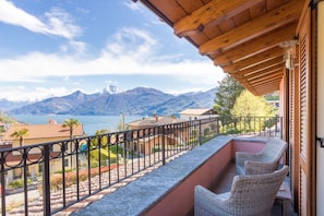 Un balcon avec des fauteuils en osier, une vue sur les montagnes et un lac.