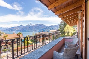 Ein Balkon mit Korbstühlen, Blick auf Berge und einen See.