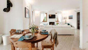 Ein Essbereich mit einem Holztisch, Stühlen und einer weißen Couch im Hintergrund.