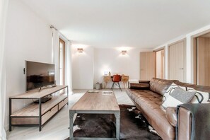 Ein modernes Wohnzimmer mit einer Couch, einem Couchtisch, einem Fernseher und einem Schreibtisch.