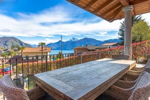 A wooden table and wicker chairs on a balcony with a mountain view.