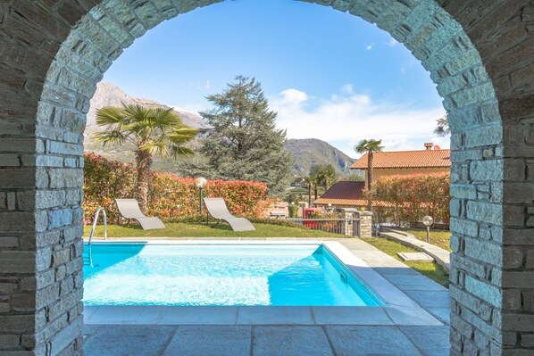 A swimming pool with a view of mountains and a house in the background.