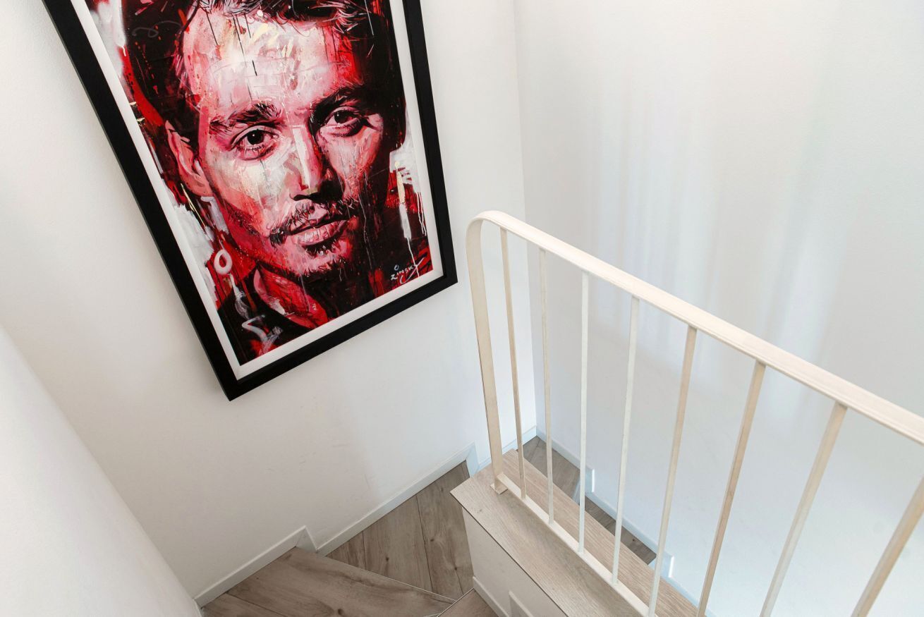 Una scala con ringhiera bianca e un quadro appeso al muro.