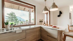 Eine moderne Küche mit großem Fenster, Holzschränken, einer Spüle und Pendelleuchten.