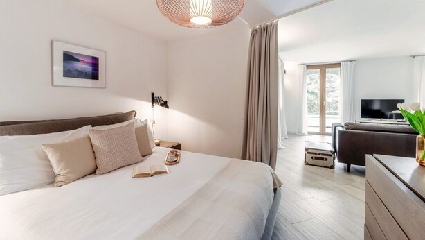 A modern hotel room with a large bed, a television, a desk with a computer, and a view of the outdoors. - Villa Rosalia - MyHomeinComo (Menaggio)
