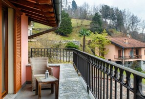 Ein Balkon mit Korbmöbeln, einem Tisch und einer Laterne.