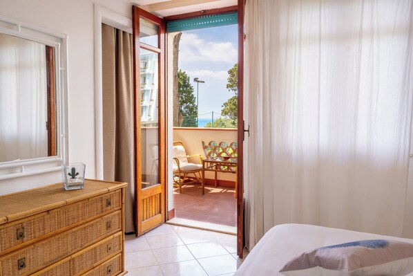 Un dormitorio con una cama, un aparador de madera y un balcón con mesa y sillas.