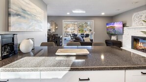 Une cuisine moderne dotée d’un plan de travail en granit, d’une cheminée et d’une grande fenêtre donnant sur un patio.