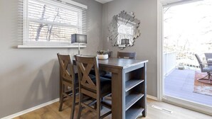 Un coin repas comprenant une table et des chaises, un élément décoratif mural et une vue à travers une porte vitrée.