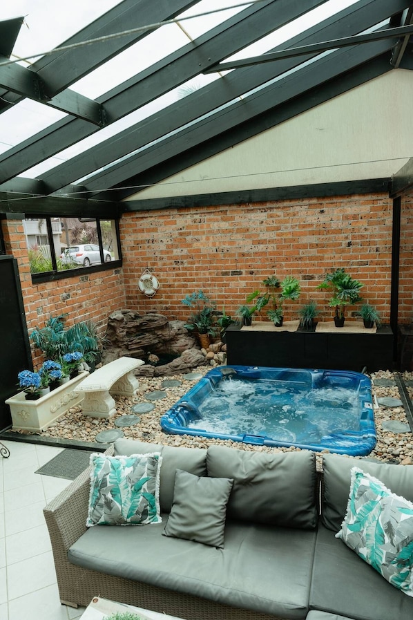 Relax in an outdoor space with a hot tub, sofa, and pergola.