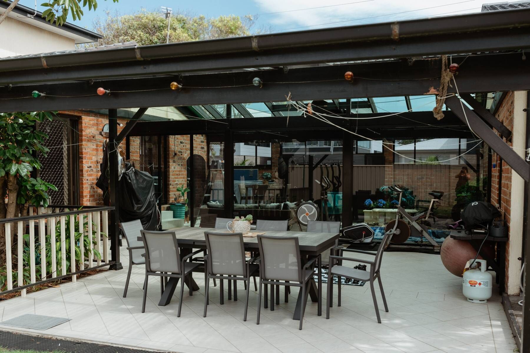 An outdoor patio area with a covered seating arrangement, a table, and chairs.