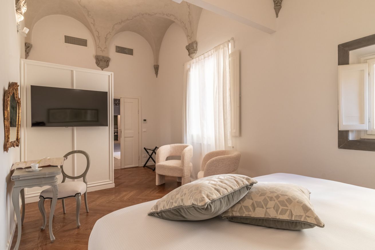 Une chambre à coucher avec un lit, deux chaises, une télévision et une armoire.
