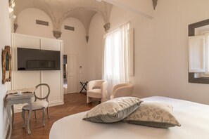 Een slaapkamer met een bed, twee stoelen, een televisie en een kledingkast.