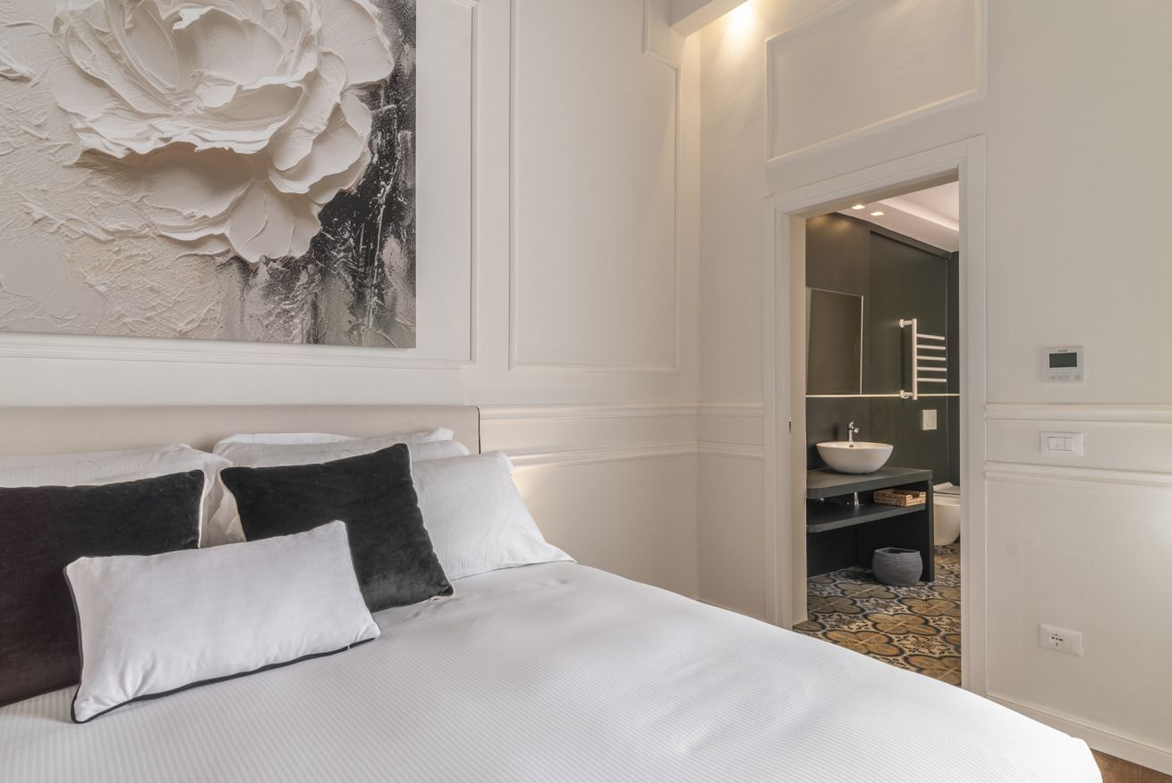 Une chambre avec un grand lit, un mur blanc et un tableau.