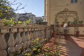 Een binnentuin met een ijzeren prieel, plantenbakken en een stenen balustrade.