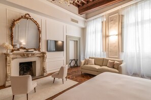Een hotelkamer met een groot bed, een open haard, een bank en een televisie.