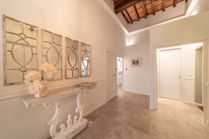 Un couloir avec une console blanche, des miroirs décoratifs et une porte au fond.
