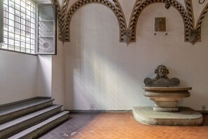Una habitación con una fuente, una ventana con rejas y una escalera.