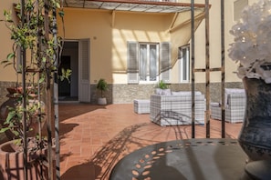 An outdoor patio with terracotta flooring, wicker furniture, and potted plants. - La casa di Liszt - Suite Marie d'Agoult (Firenze)