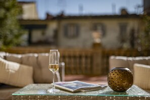 Une table en verre sur laquelle se trouvent un verre à vin, un magazine et un vase décoratif.