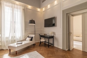 A modern bedroom with a sofa, a desk, a lamp, and a TV. - La casa di Liszt - Suite Marie d'Agoult (Firenze)