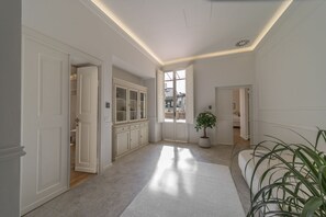 A hallway with white walls, a large window, and a potted plant.