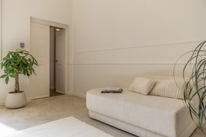 A neutral-toned living room with a sofa, a potted plant, and a door leading to another room. - La casa di Liszt - Suite Madame Riblet (Firenze)