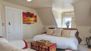 A bedroom with a large bed, a chest of drawers, a small table, and a painting on the wall. - Large Space Great for Special Occasions: 2 Floors (Montclair)