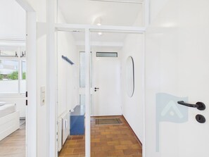 A corridor with a white door, a blue trash bin, and a radiator.