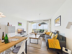 Ein zeitgemäßer Wohnraum mit Essbereich, Sofa und Balkon mit Blick.